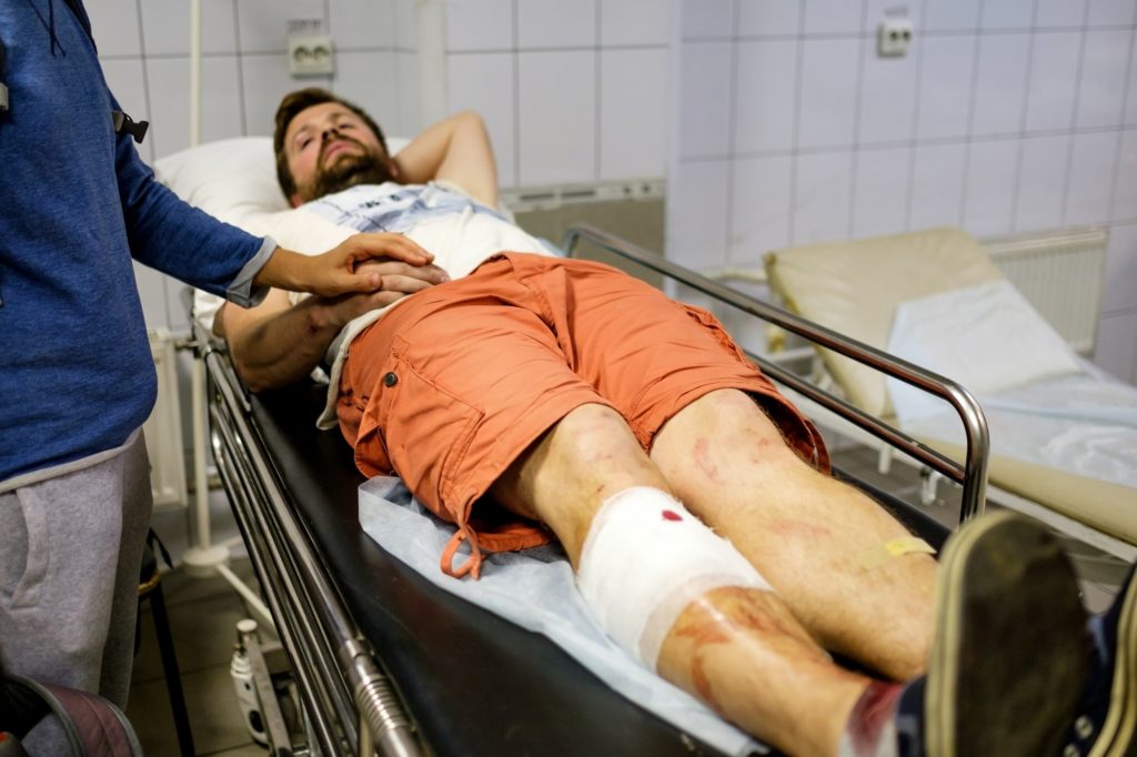 Young man lying in a hospital bed in the building of ambulance after a car accident
